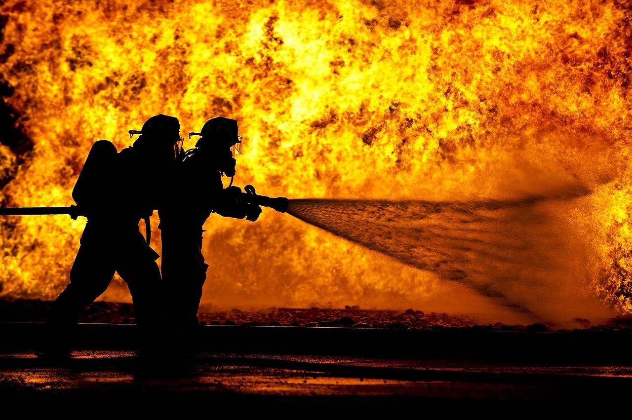 Firemen with hose fighting a large fire